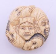 A bone carving decorated with faces. 4 cm diameter.