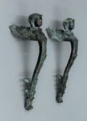 A pair of patinated bronze fittings headed with angel masks. 37 cm long.