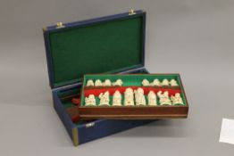 A cased chess set. The case 37 cm wide.
