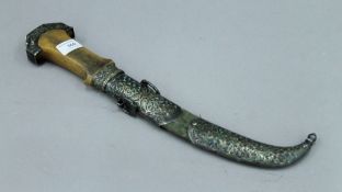 An antique jambiya, the handle possibly rhino horn and with unmarked white metal mounted scabbard,