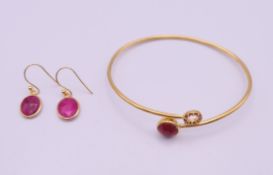 A silver gilt bangle and a pair of matching earrings. The bangle 6.5 cm wide.