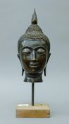 A patinated bronze bust of Buddha on a display stand. 40 cm high overall.