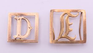 Two 9 ct gold mounts, initialled D and E. The latter 1.5 cm wide. 1.2 grammes.