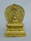 A gilt bronze model of Buddha before a shire. 28 cm high.