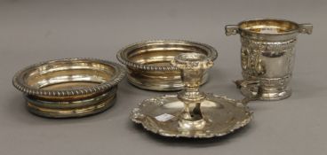 A silver plated chamberstick, a pair of plated coasters and a vase.