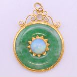 A Chinese unmarked high carat gold mounted jade and opal pendant. 3.75 cm diameter. 8.