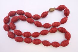 An early 20th century Chinese cinnabar necklace with silver gilt clasp. 62 cm long.