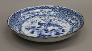 A large Japanese blue and white porcelain dish decorated with peacock perched on blossoming prunus