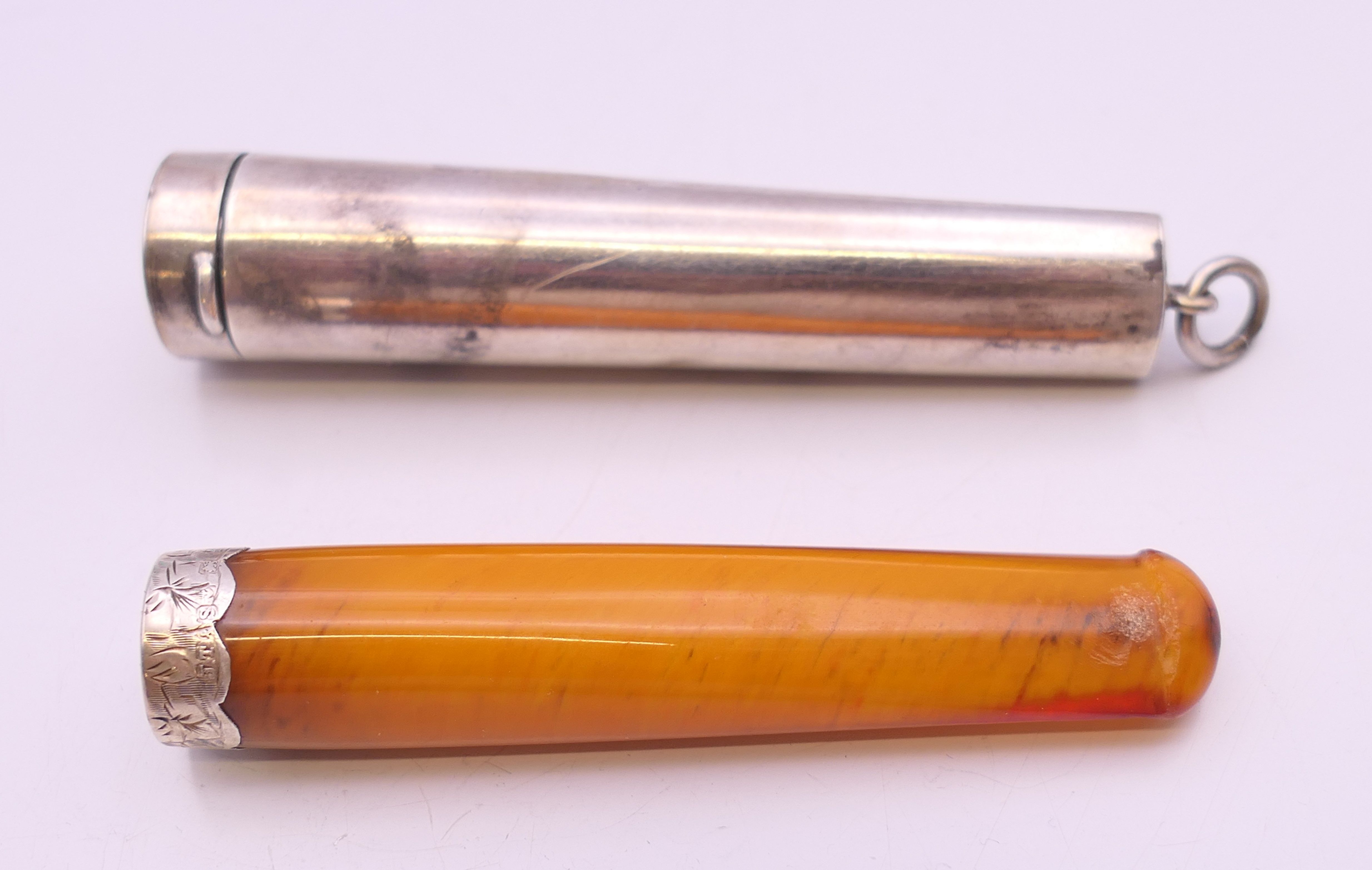 A silver cigarette holder case, containing a silver mounted amber cigarette holder. 7 cm long. 16.