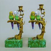 A pair of candlesticks each mounted with porcelain budgerigar.