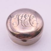 A small Edwardian silver round pill box, Birmingham 1900, top and bottom engraved with initials.