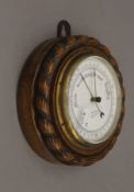 An aneroid wall barometer with oak case and rope twist decoration to perimeter,