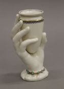 A porcelain vase formed as a hand holding an urn. 15 cm high.