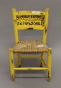 A small yellow painted child's chair, the back inset with an advertising print for J S Fry & Son.