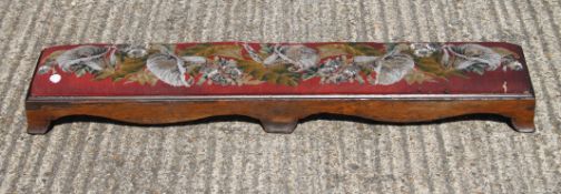 A Victorian rosewood long footstool and embroidered top. 120 cm long.