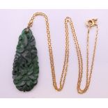 A carved and pierced spinach jade pendant on an 18 ct gold chain. The pendant 4 cm high.