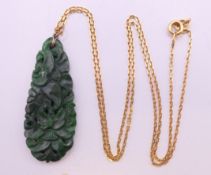 A carved and pierced spinach jade pendant on an 18 ct gold chain. The pendant 4 cm high.