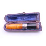 A cased amber cigar holder with silver collar. 8 cm long.