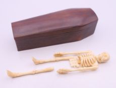 A wooden model of a coffin with bone model skeleton. 12 cm long.
