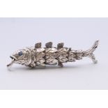 An articulated silver fish with sapphire eyes. 6 cm long. 14.8 grammes total weight.