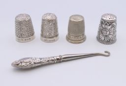 Four silver thimbles and a silver handled button hook.
