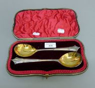 A cased pair of silver serving spoons. 21 cm long. 167.6 grammes.