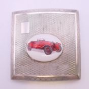 A silver enamel cigarette case decorated with a car. 8 cm wide.