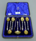 A cased set of Apostle teaspoons, sifter spoon and tongs. The tongs 10.5 cm high. 123.9 grammes.