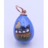 A Russian enamel egg pendant decorated with a chicken. 2.5 cm high.