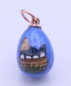A Russian enamel egg pendant decorated with a chicken. 2.5 cm high.