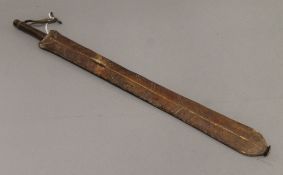 A tribal short sword, possibly Maasai, in leather scabbard. 56 cm long.
