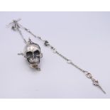 A silver skull and chain. The skull 4 cm long.