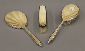 Two silver and enamel brushes, and a mirror. The latter 28 cm long.