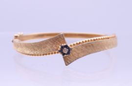 A 14 K gold diamond and sapphire set bangle form bracelet. Approximately 5.75 cm internal width. 22.