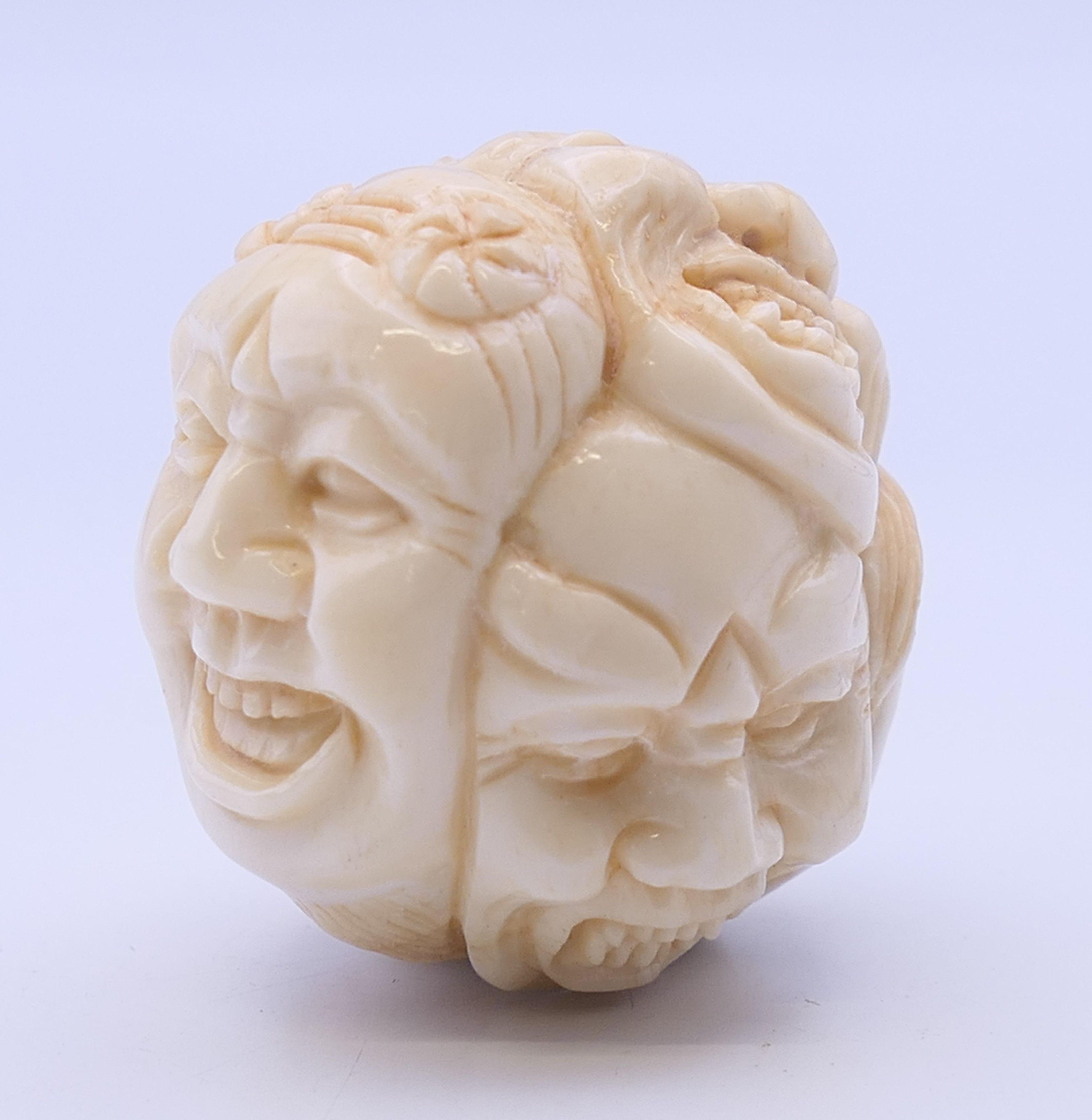 A bone carving formed as various faces. 3.5 cm high.