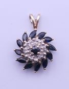 A 9 ct gold diamond and sapphire pendant. 1.75 cm high. 1.6 grammes total weight.