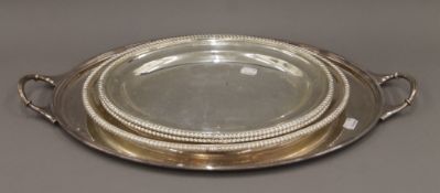 A silver plated tray and three plated serving platters. The former 60 cm wide.