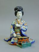 A 19th century Japanese porcelain figure of a girl and a drum. 19 cm high.