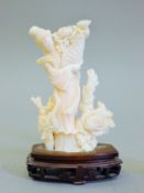 A Chinese white coral model of Guanyin mounted on a carved wooden stand. 12.5 cm high.