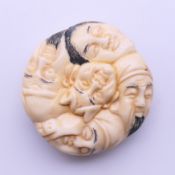 A bone carving formed as various faces. 4 cm diameter.