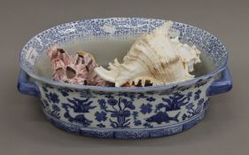 A quantity of sea shells in a blue and white jardiniere. The jardiniere 39 cm long.