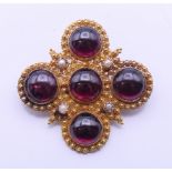 A 19th century unmarked gold, garnet and seed pearl set brooch. 3.75 cm wide.