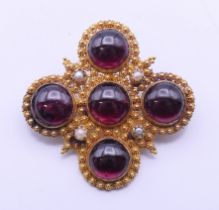 A 19th century unmarked gold, garnet and seed pearl set brooch. 3.75 cm wide.