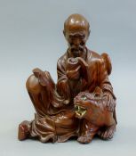 A Chinese wooden figure of a man reading. 21 cm high.