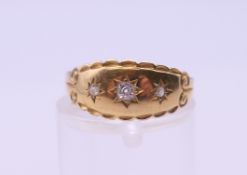 An 18 ct gold three stone diamond gypsy set ring. Ring size N/O. 2.1 grammes total weight.