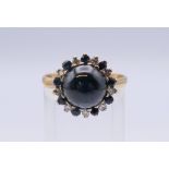 An unmarked gold cabochon sapphire and diamond ring. Ring size R/S.