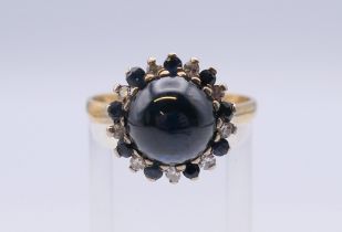An unmarked gold cabochon sapphire and diamond ring. Ring size R/S.