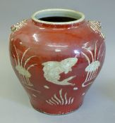 A Chinese red ground pottery vase decorated with fish. 24 cm high.