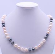 A two-tone string of cultured pearls. 71 cm long.