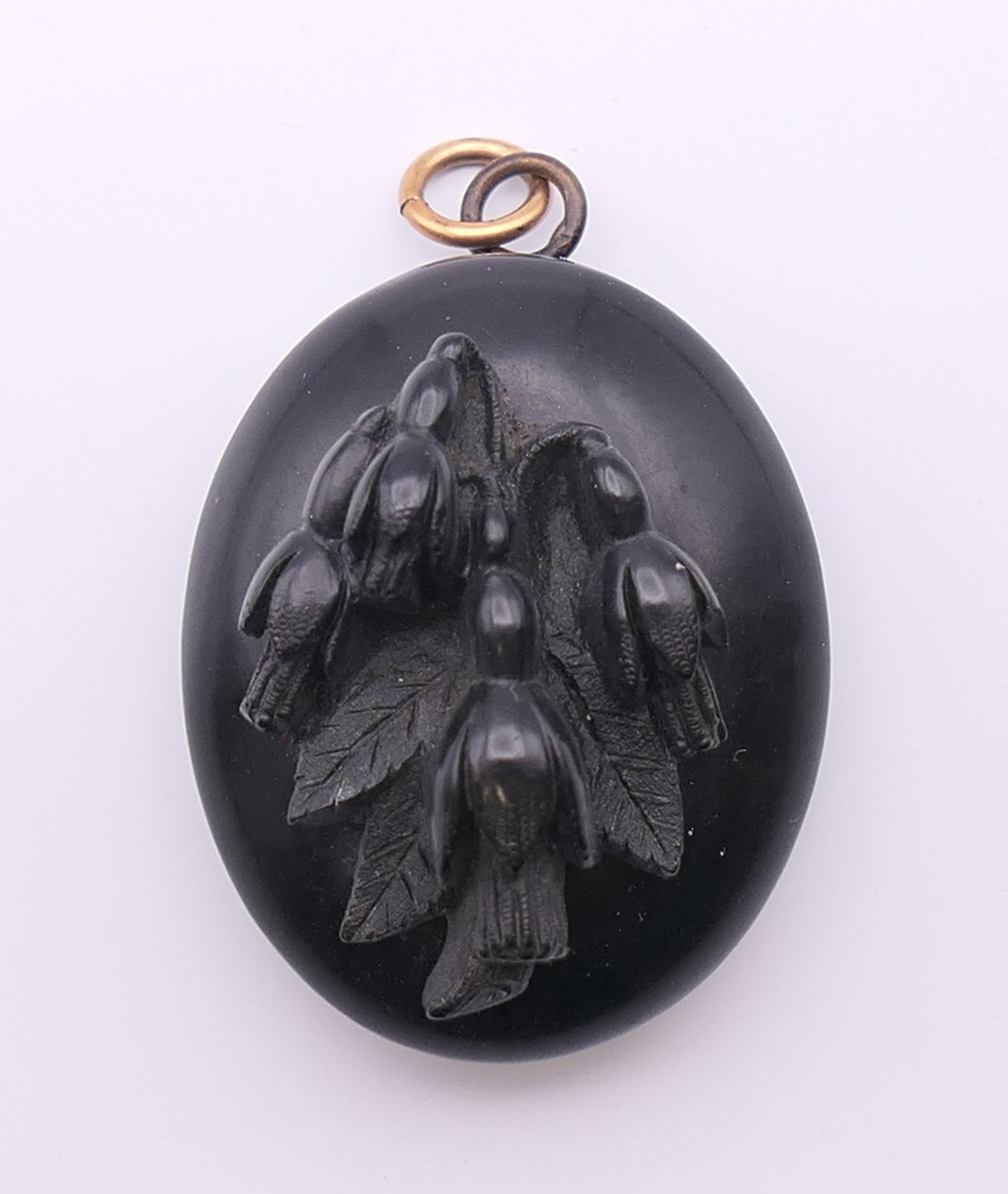 A locket with floral motif to the front. 3.5 cm high.